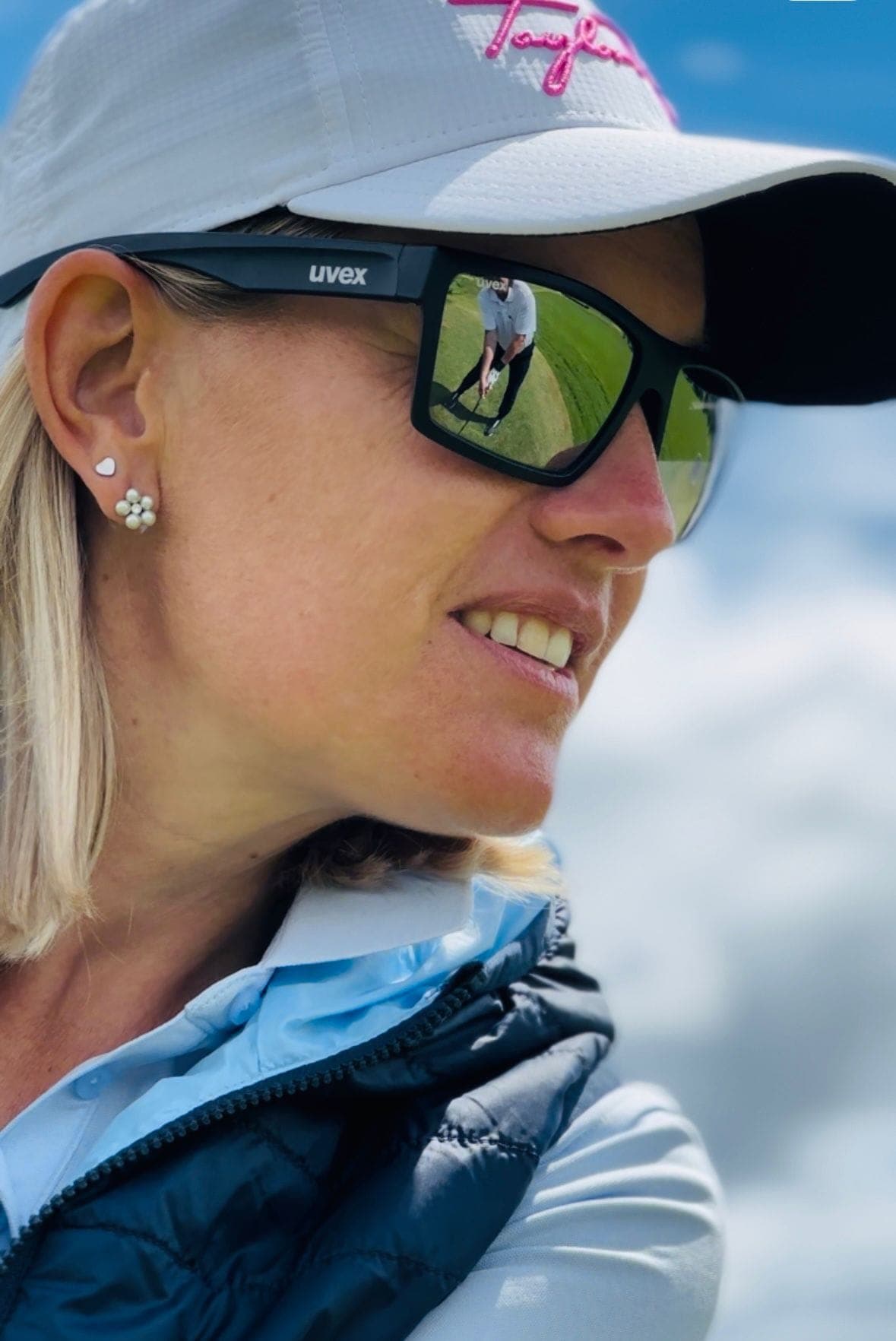 Nicole Gergely in Nahaufnahme — in ihrer Sonnenbrille spiegelt sich der Golfplatz
